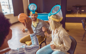 Team members with head-mounted nets playing a fun team-building game with a ball, fostering collaboration in a lively indoor setting.