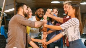Diverse team stacking hands in a modern office, symbolizing unity and collaboration among colleagues in a professional setting.