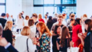 Blurred crowd of professionals networking at a corporate event venue.